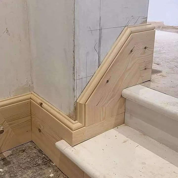 Close-up of baseboard and stair skirt trim mitred tightly into a stair stringer