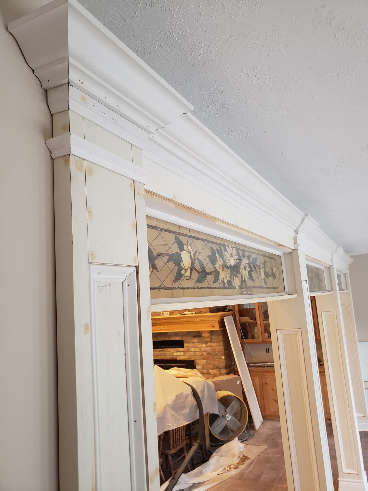 Lengths of primed crown moulding, casing and baseboard staged along a wall ready for installation
