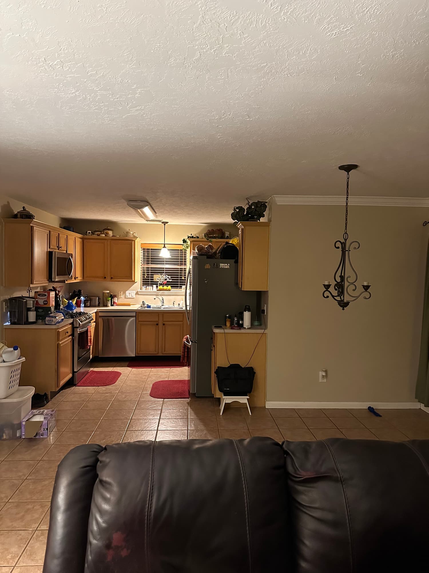The same kitchen before work started, with dated honey-oak cabinets, tile countertops and a wrought-iron pendant light