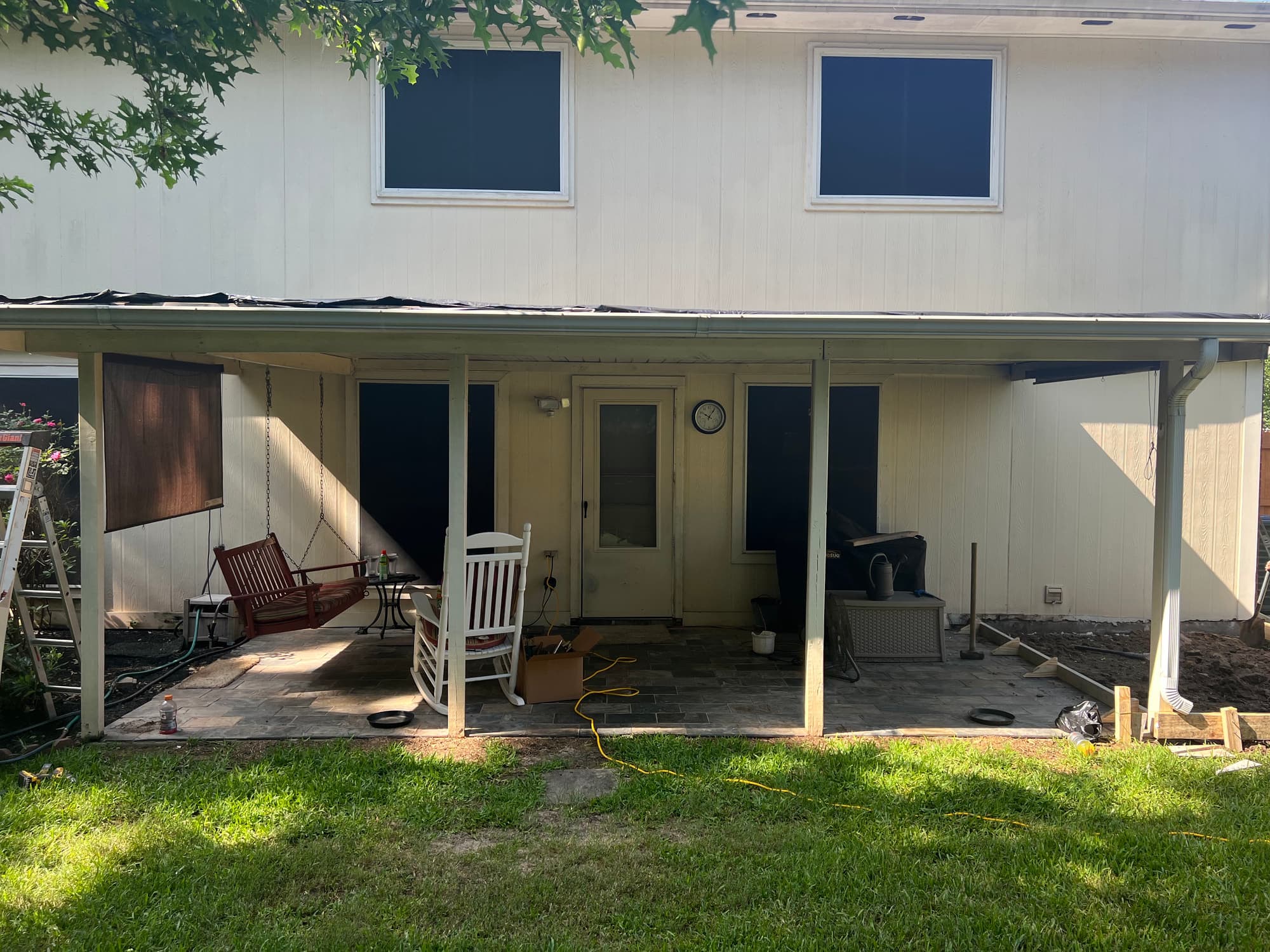 Back of a Houston home before the patio cover was built, showing an existing paver patio under a low aluminium awning