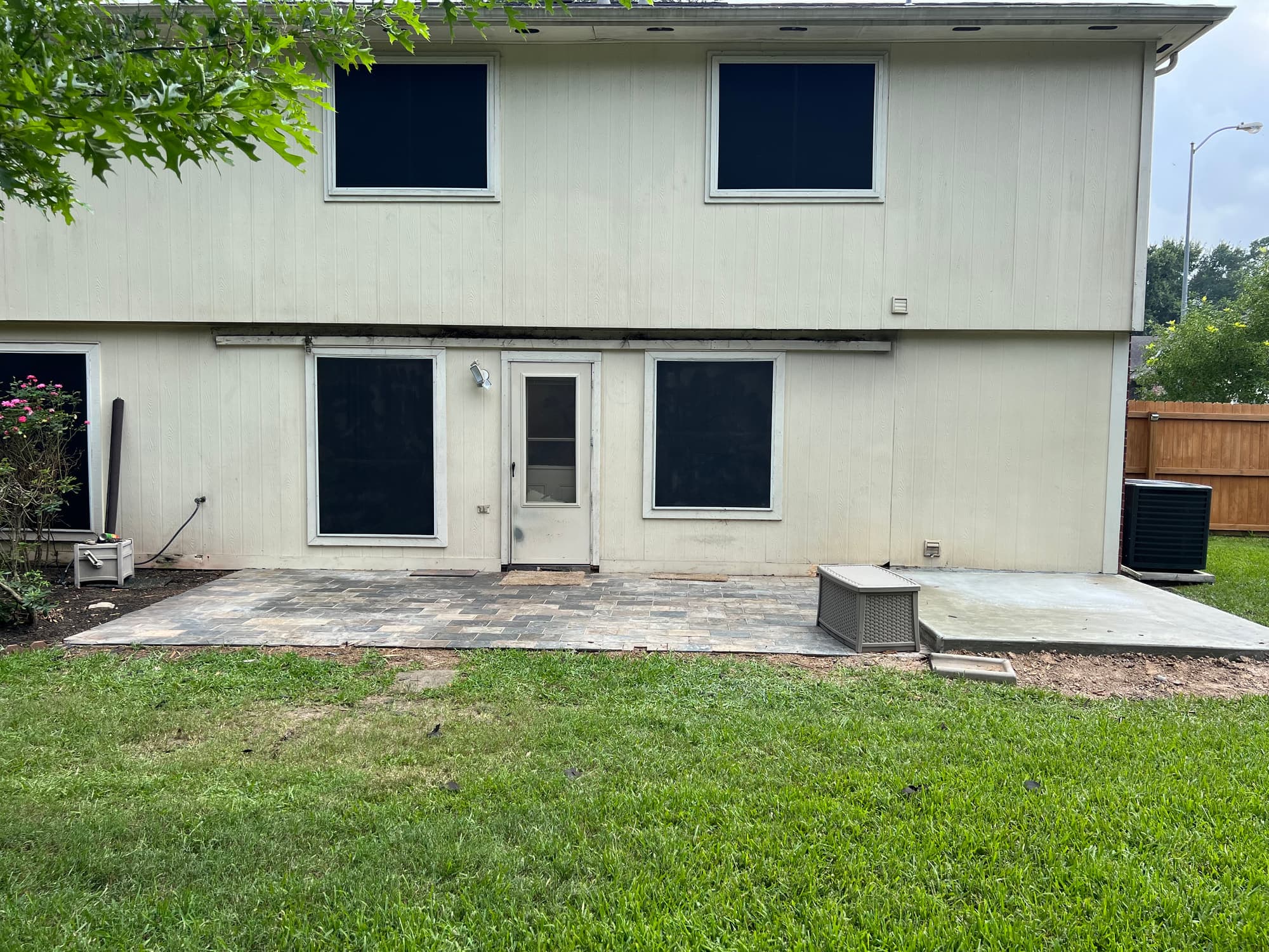 Rear elevation of the same two-storey home before construction, with the awning removed and the bare paver patio exposed