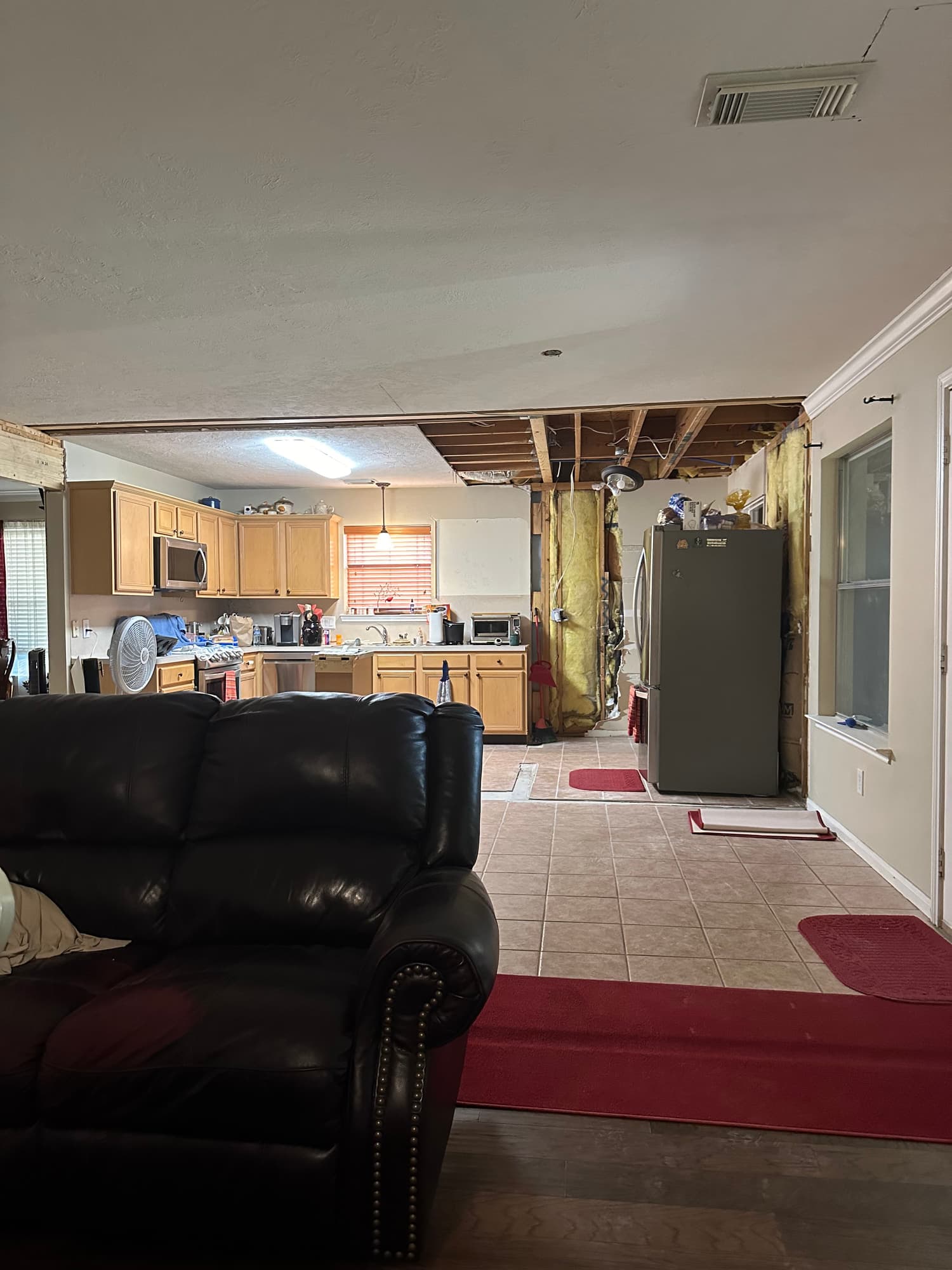 Kitchen demolition in progress with the soffit removed, ceiling opened and wall studs and batt insulation exposed